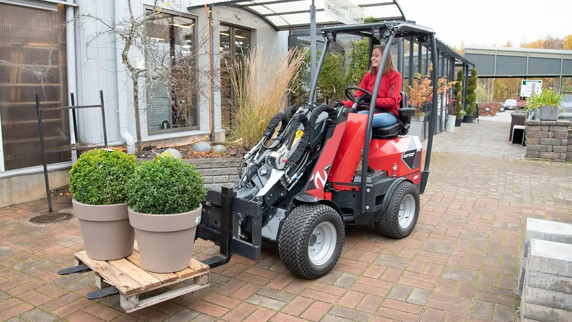 Potteplanter på pall kjøres med minilaster